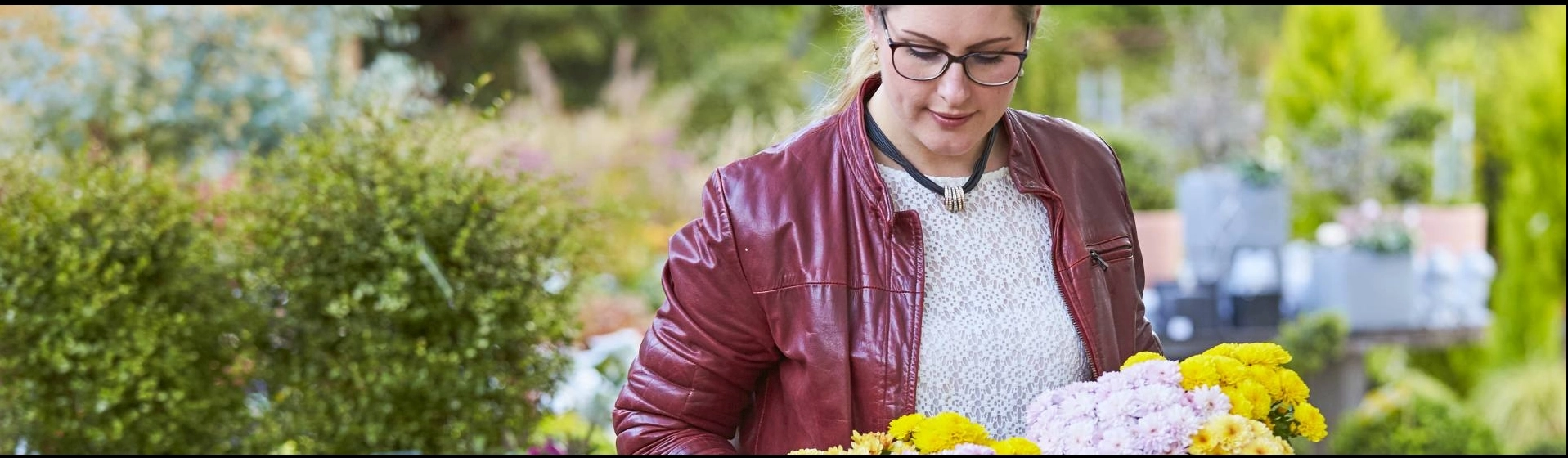 Frau schaut auf blühende Pflanzen, die sie in einem Gartencenter in der Hand hält