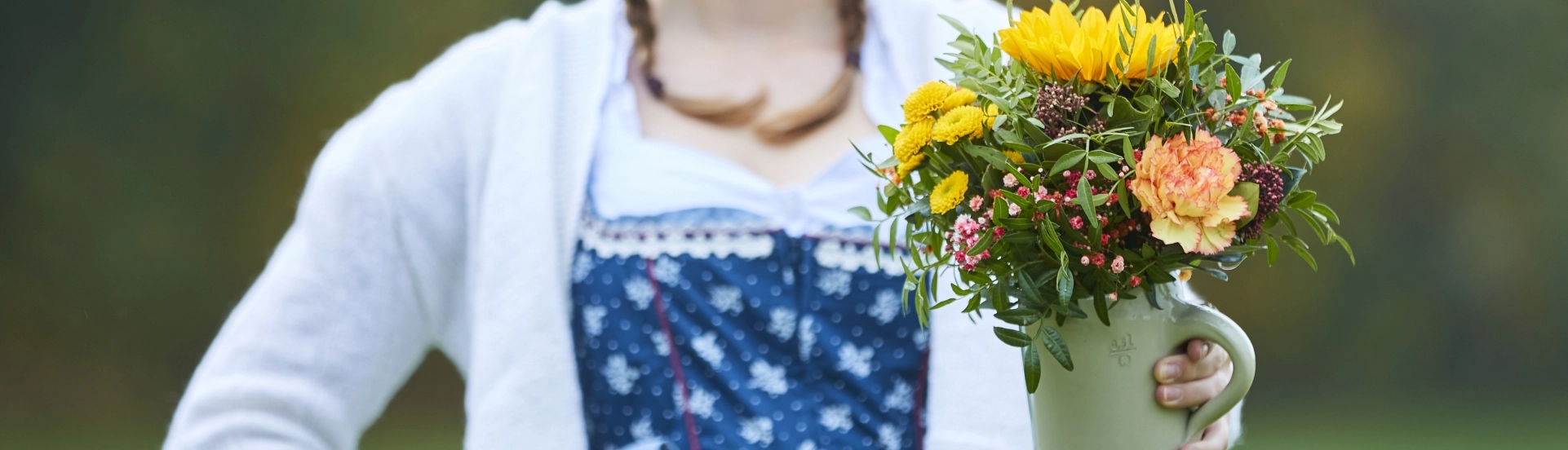 Junge Frau im Dirndl hält Bierkrug mit Strauß in der Hand